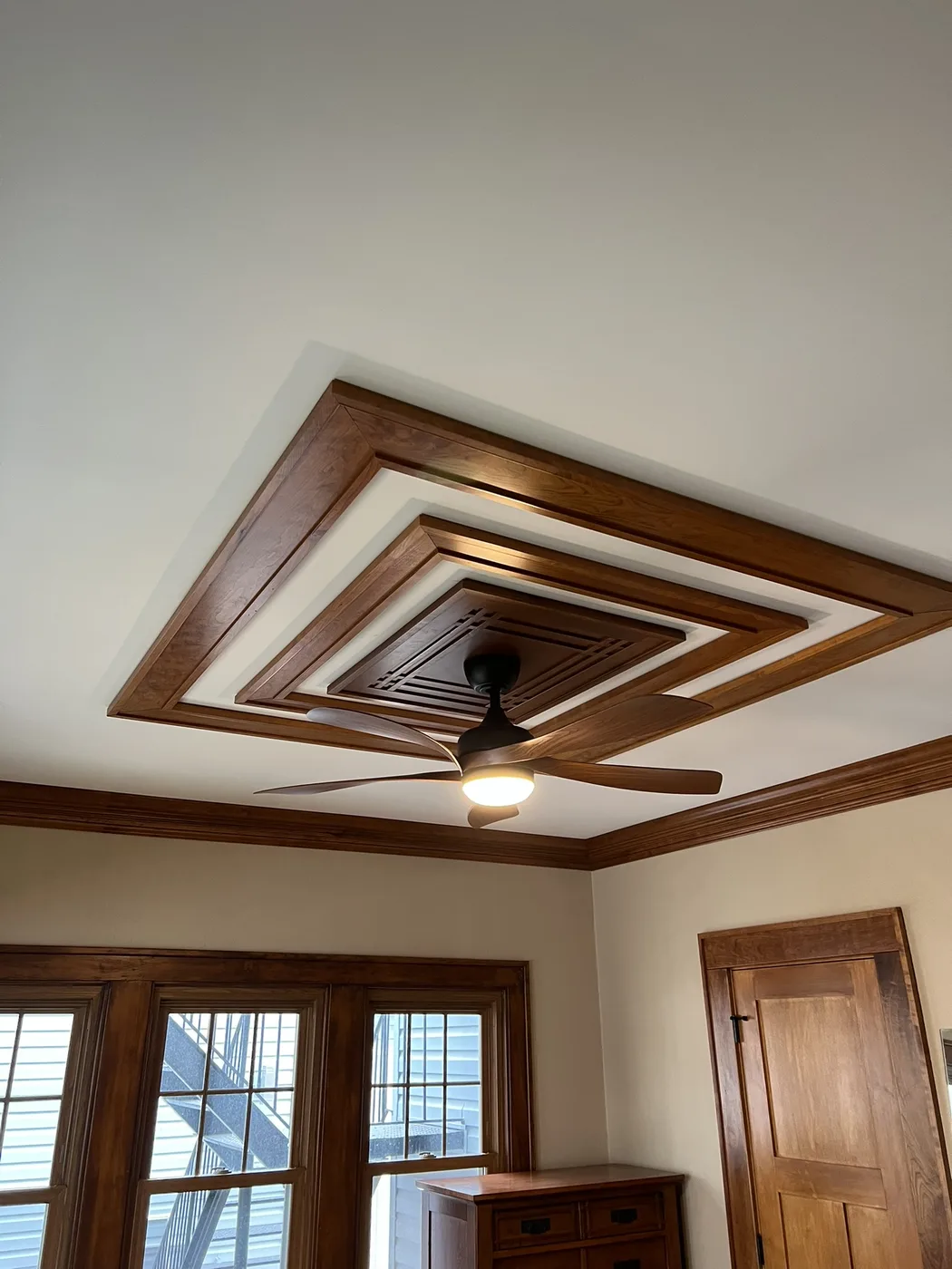 Custom wood coffered ceiling with a stepped square pattern and a centre ceiling fan