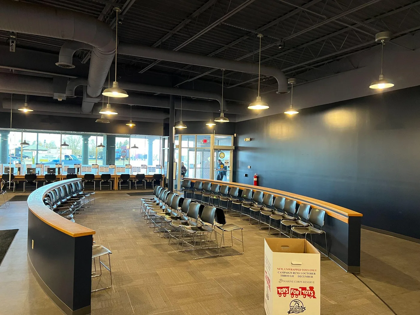 Commercial dining room with a dark painted wall, a curved counter with stools and pendant lights
