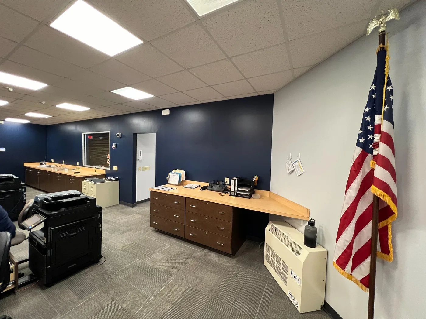 Office interior with a navy accent wall, white walls, a reception desk and a flag