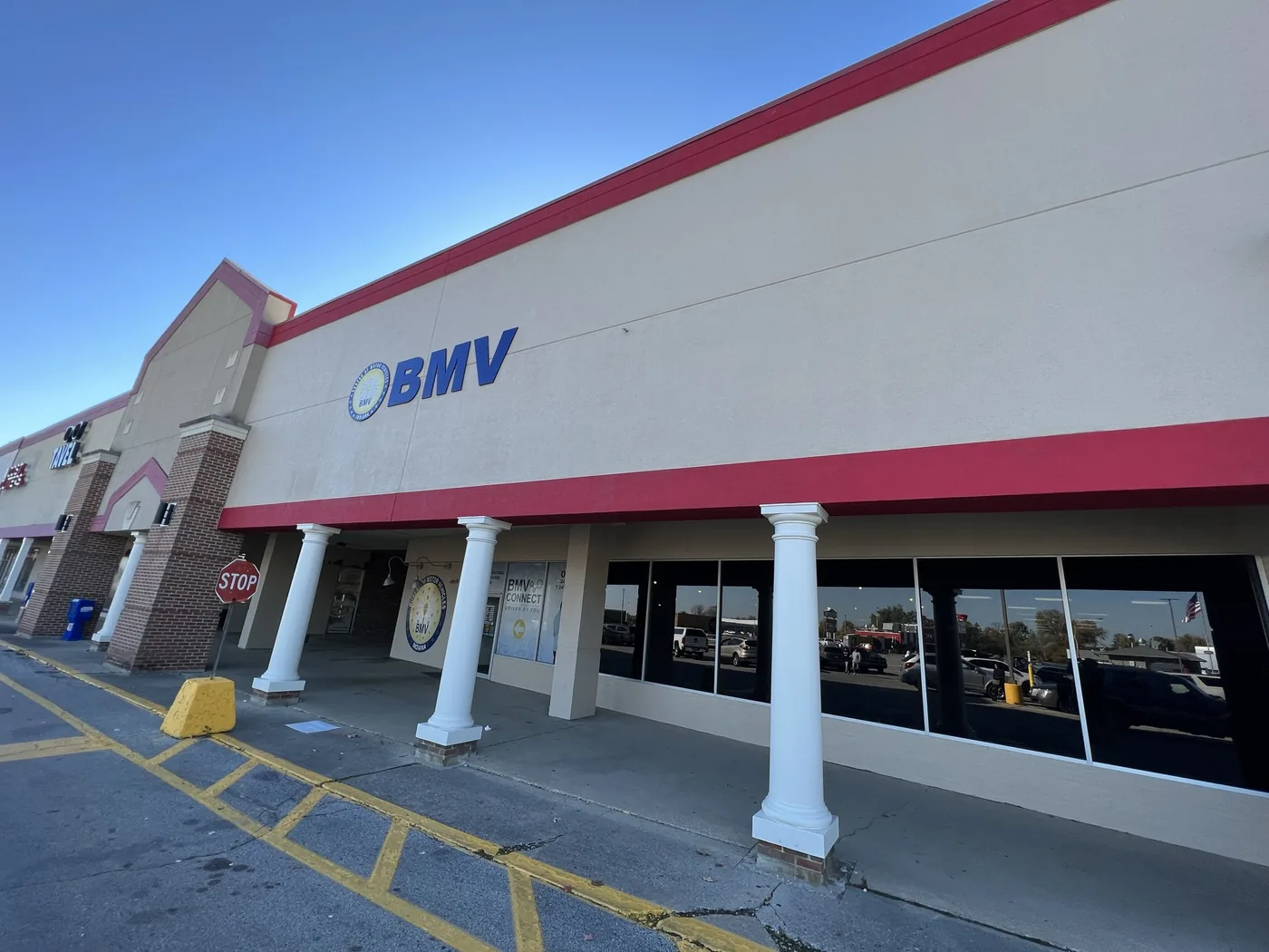 Commercial storefront painted white with a red accent band above the entrance columns