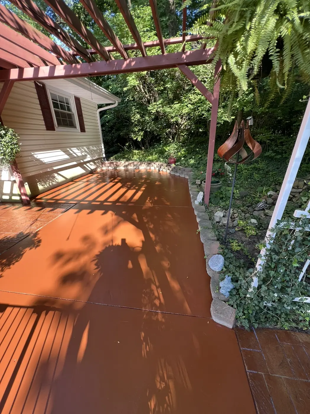 Backyard deck freshly stained a red brown color beneath a matching stained pergola