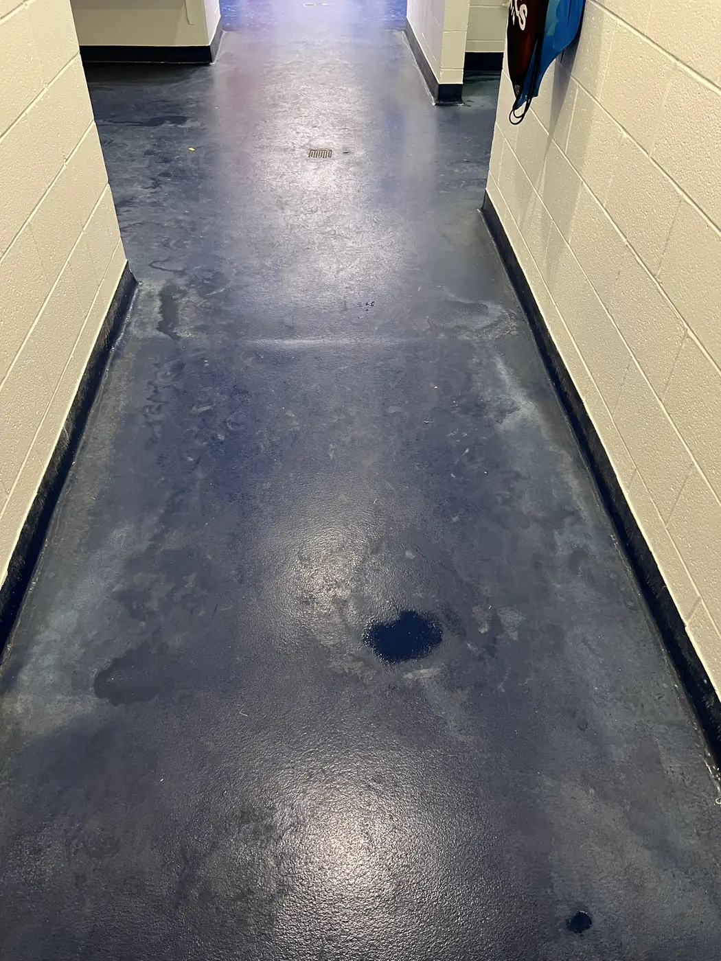 Commercial hallway with a dark navy epoxy floor coating running between block walls