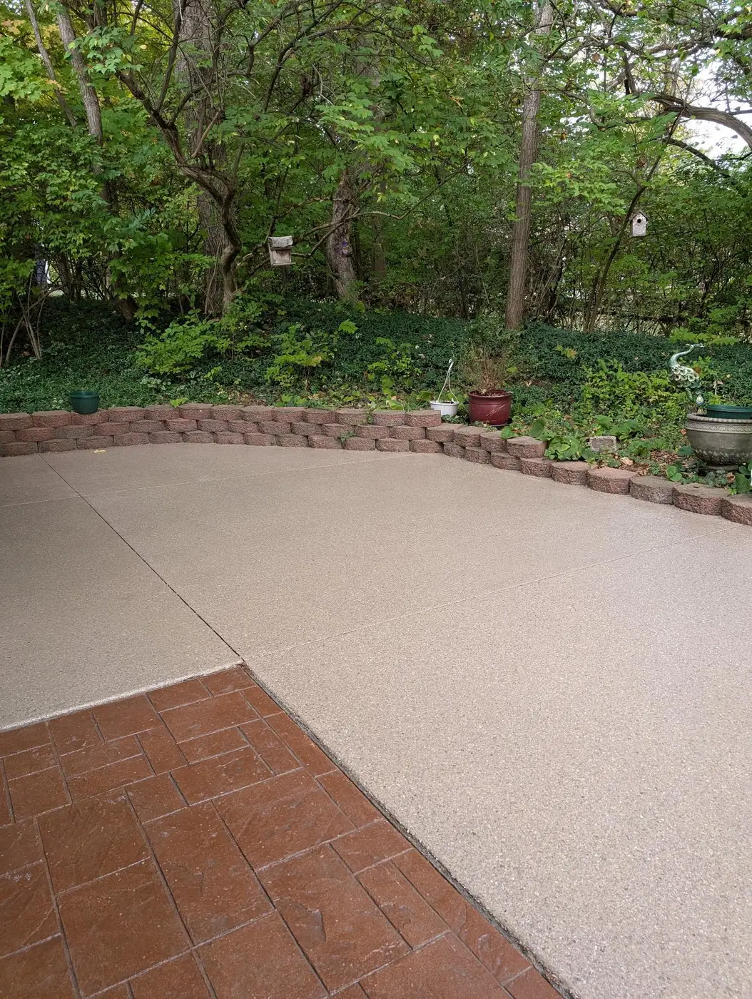 Patio slab finished with a tan and grey flake coating, meeting a brick paver walkway
