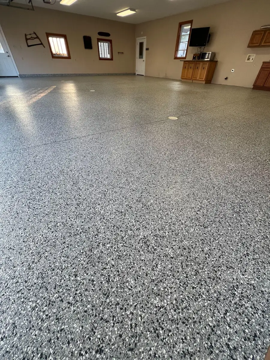Large finished room with a grey flake floor coating and wood cabinets along the far wall