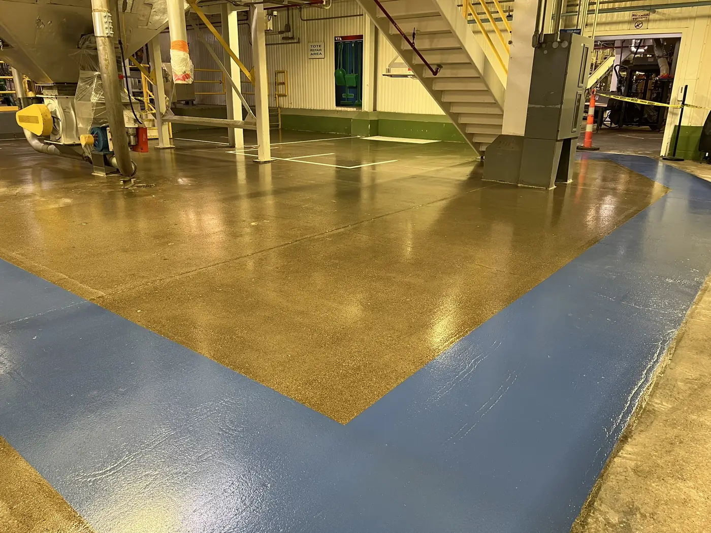 High gloss gold epoxy floor coating with grey blue walkway striping in a manufacturing plant