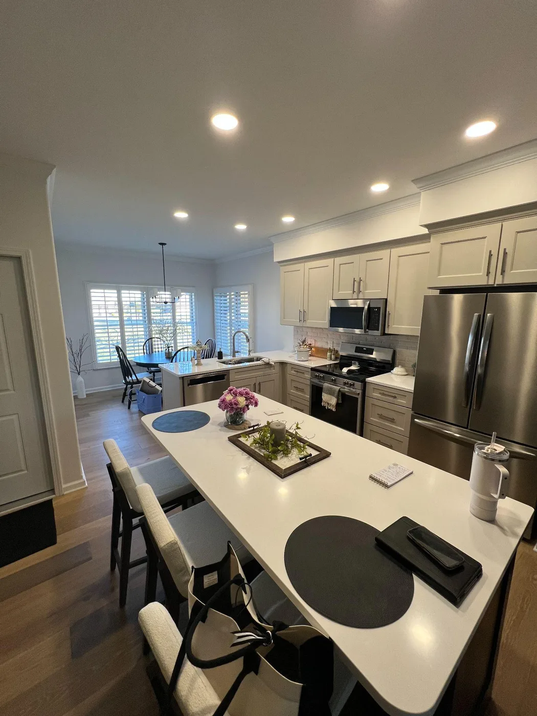 Kitchen with cream cabinets, a long island with seating and stainless appliances